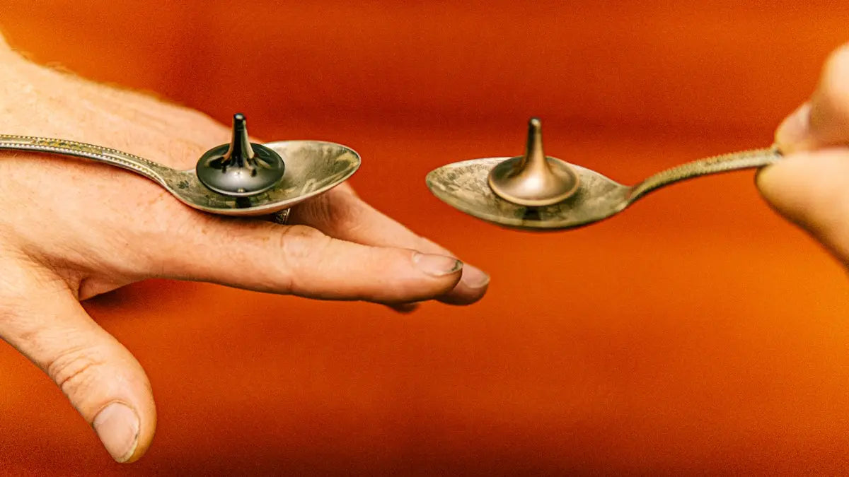 a pair of spoons being held by a person's hand