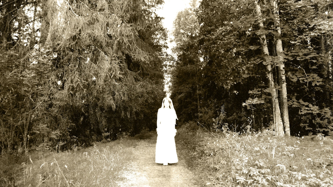 Figure in white dress on path through trees