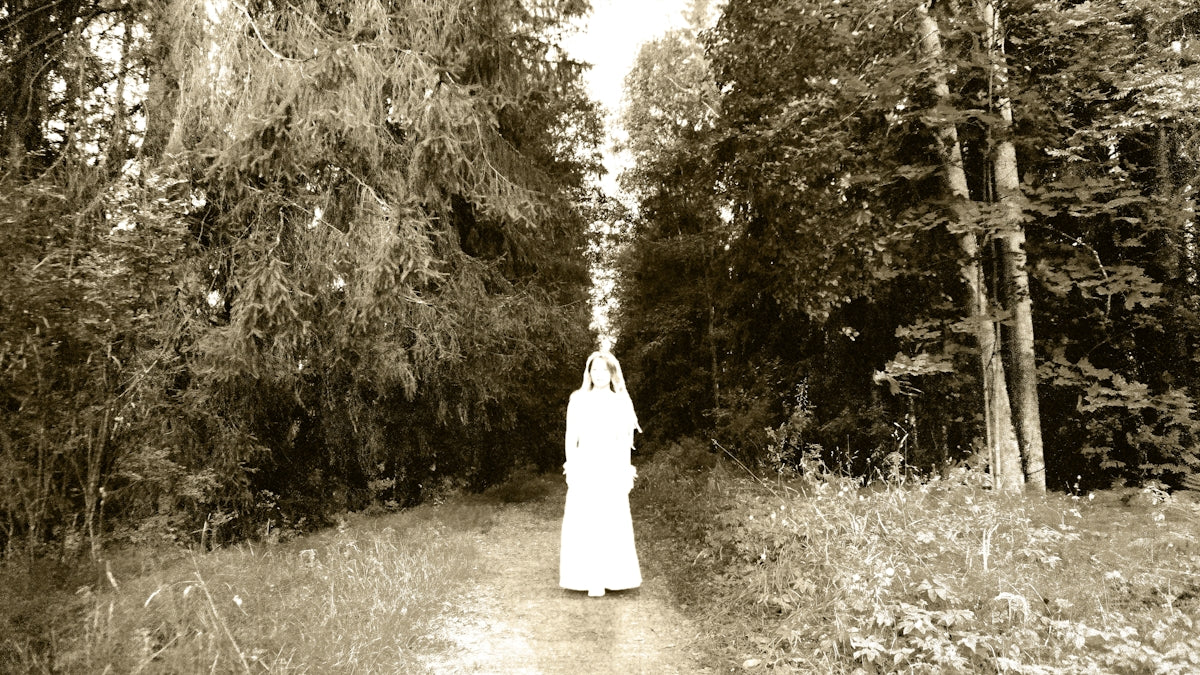 Figure in white dress on path through trees
